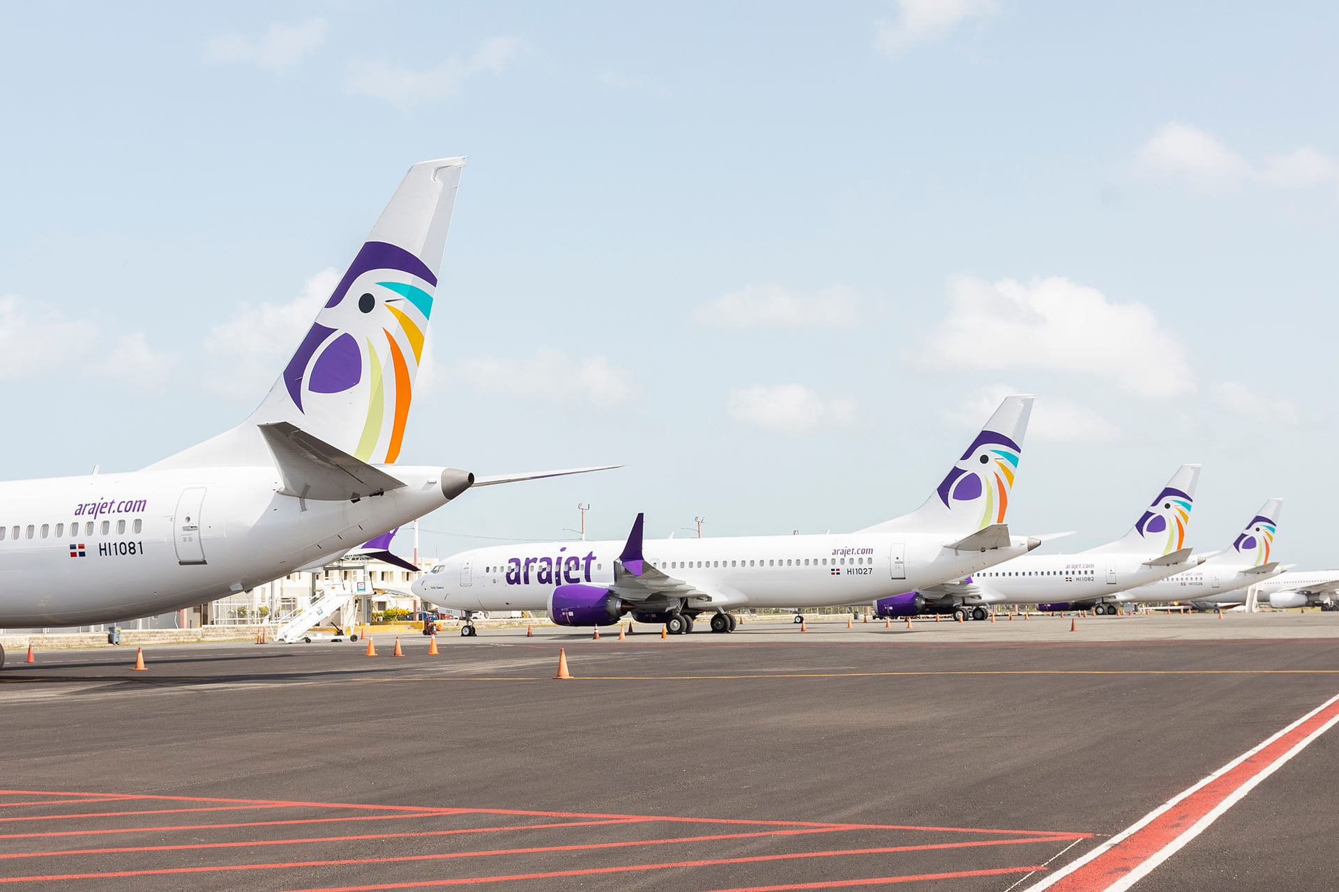Perspectiva de las colas de los aviones Boeing 737 MAX 8 de Arajet estacionados en la pista, resaltando el logotipo distintivo de la aerolínea dominicana.