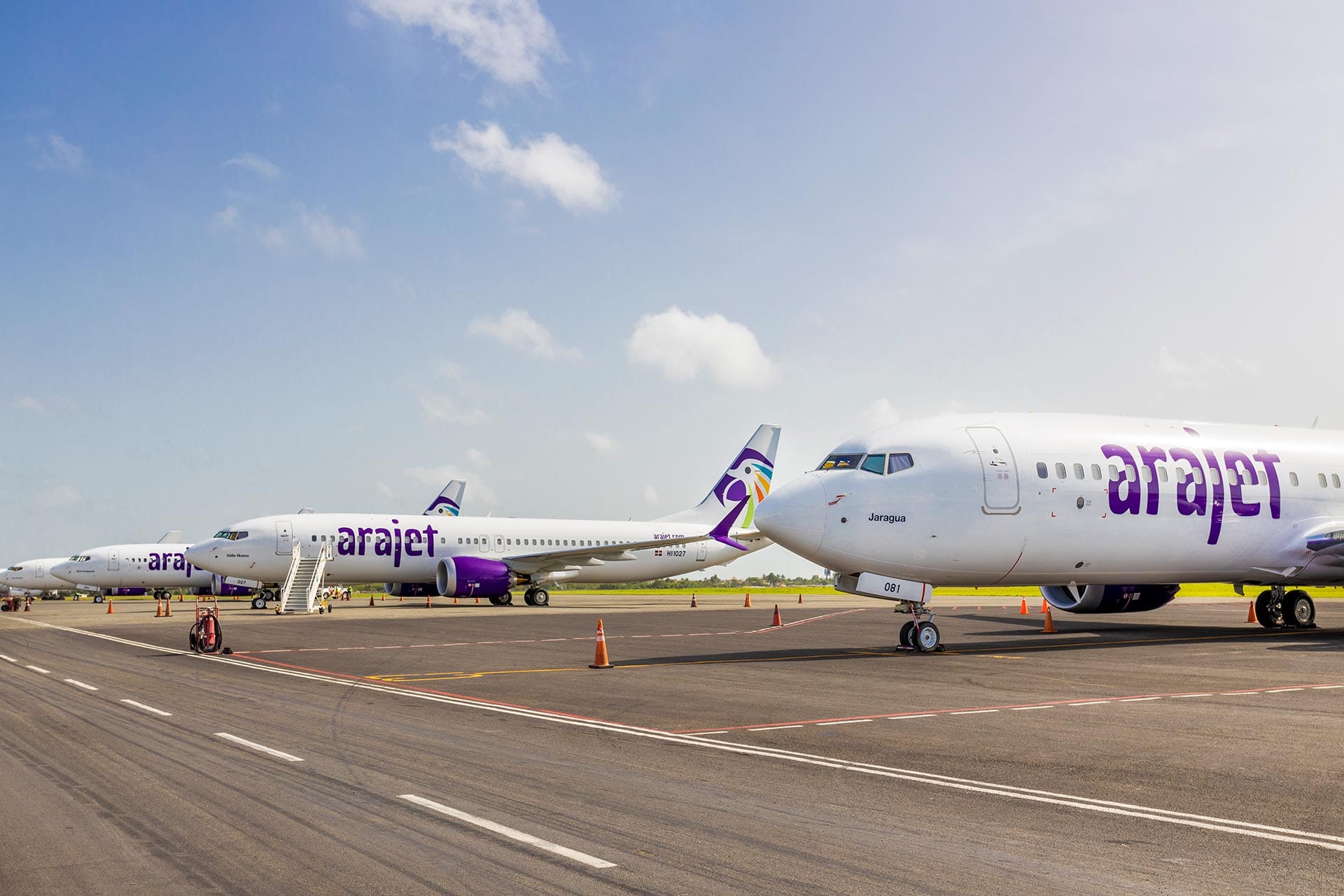 Varias aeronaves Boeing 737 MAX 8 de la aerolínea dominicana Arajet estacionadas en fila sobre la pista de aterrizaje.